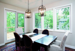 The dining area of a home with beautiful windows and a set of patio doors