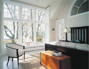 The bedroom of a home with a wall of beautiful windows streaming in light